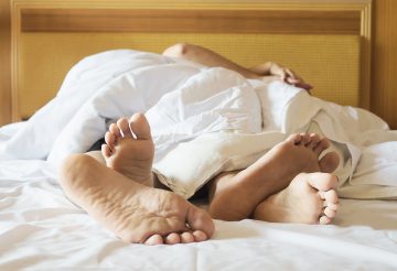 couple's feet on white bed in a hotel room